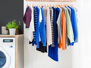 Ryškių spalvų drabužiai, kabantys greta „Electrolux“ skalbyklės-džiovyklės „DualCare“