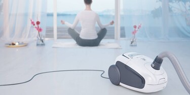 Moteris, atliekanti jogos pratimus; pirmajame plane – „Electrolux“ dulkių siurblys „Ultra Silencer“