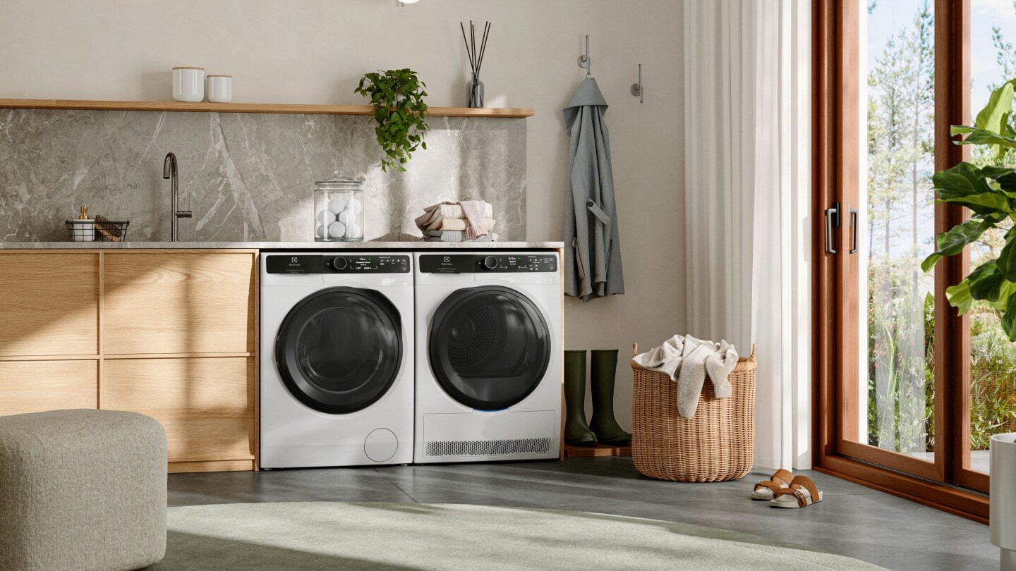 Skalbykla su skalbimo mašina ir džiovykle iš Electrolux, pastatyta vienas šalia kito po stalviršiu.